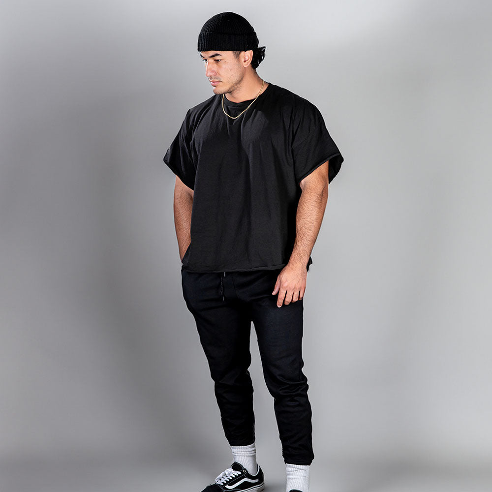 Man in black attire with GYMPUK t-shirt, pants, beanie, and sneakers.