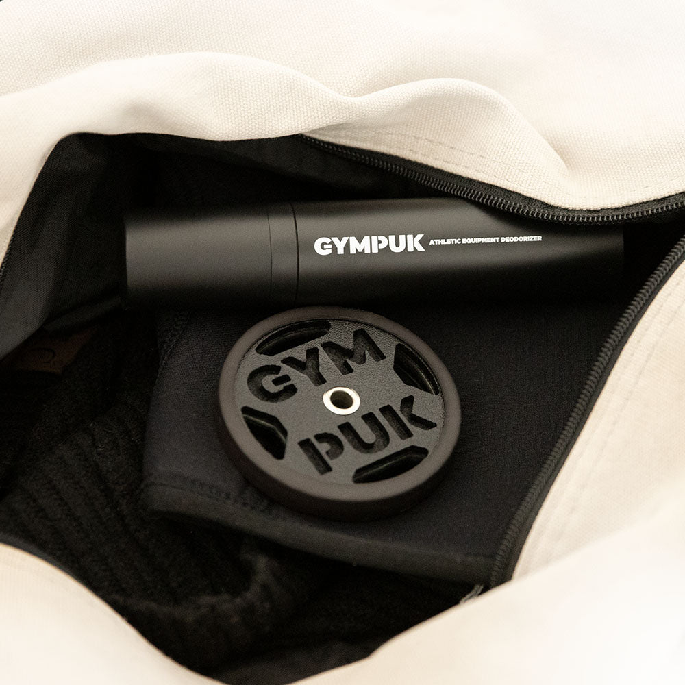 GYMPUK' deodorant bottle and weight plate-shaped deodorizer inside a gym bag.